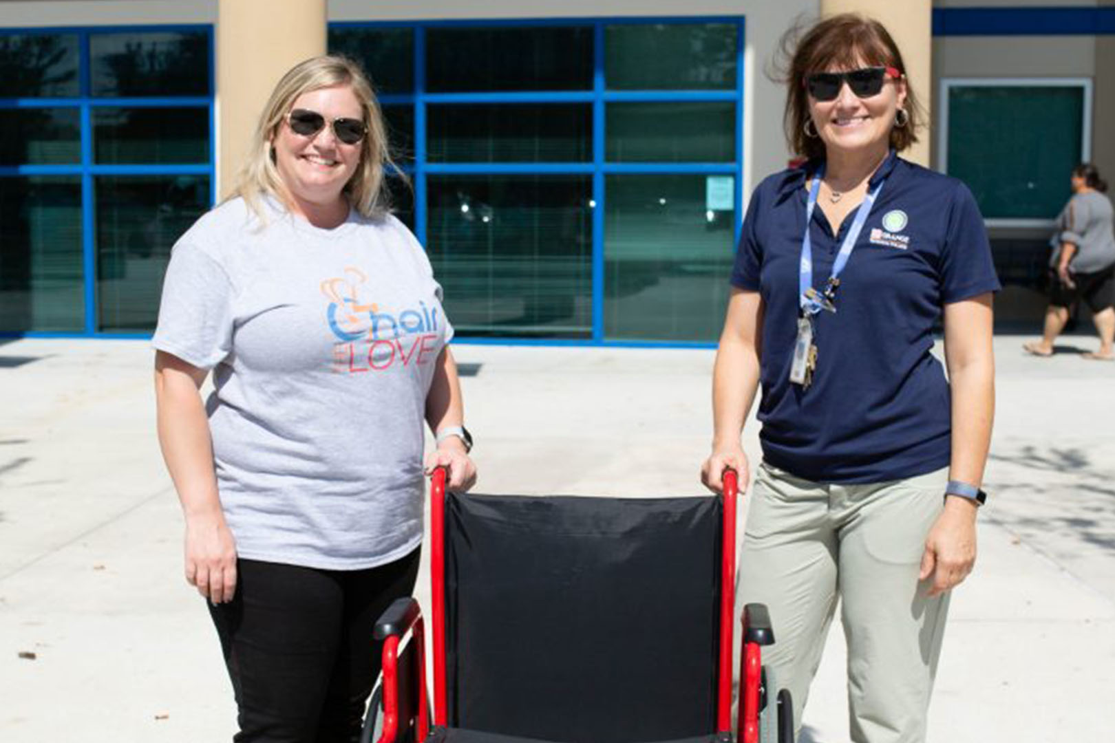 Two women posing with a wheelchair between them