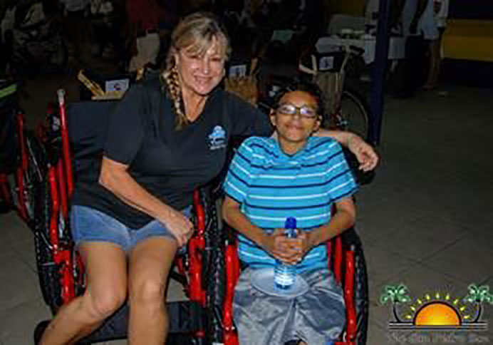 A volunteer sitting with a kid in a wheelchair